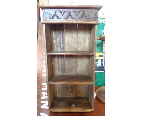 A 32cm old stained mixed wood wall mounted three shelf open bookcase with iron bound top decorated with blind fretwork foliag