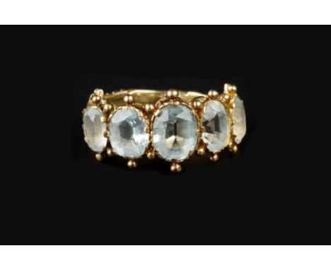 A 19TH CENTURY TOPAZ FIVE STONE RING, the graduated oval mixed-cut topaz of pale blue hues, in beaded pinched claw setting, t