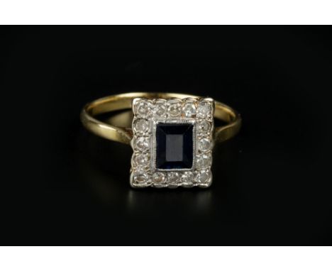A SAPPHIRE AND DIAMOND CLUSTER RING, the rectangular step-cut sapphire bordered by single-cut diamonds, stamped '18ct &amp; p