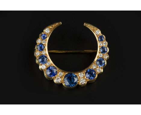 A SAPPHIRE AND DIAMOND CRESCENT BROOCH, alternately set with circular mixed-cut sapphires and pairs of round brilliant-cut di