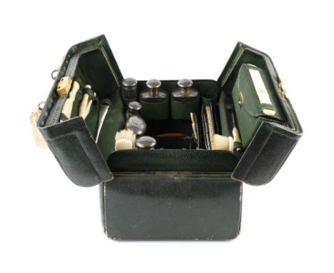 AN EDWARDIAN GREEN LEATHER DRESSING CASE, fitted with a range of silver topped faceted glass jars, including a hip flask, and