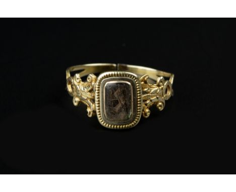 A 19TH CENTURY MEMORIAL RING, centred with a glazed plaited hairwork panel, between pierced and engraved foliate shoulders, (