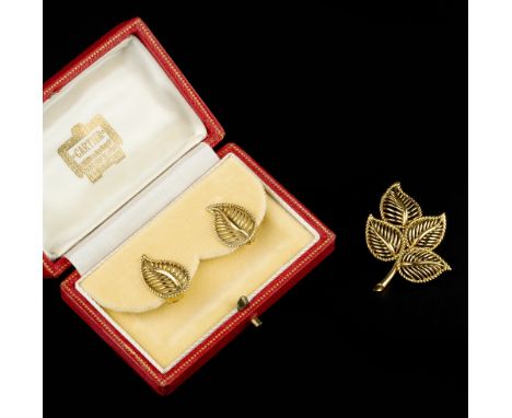 AN 18CT GOLD BROOCH AND EAR CLIPS SUITE BY CARTIER, the brooch modelled as a spray of wirework leaf-shaped panels, with maker