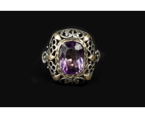 AN ARTS AND CRAFTS AMETHYST PANEL RING, the cushion-shaped panel pierced and engraved with foliage and lozenge motifs, enclos