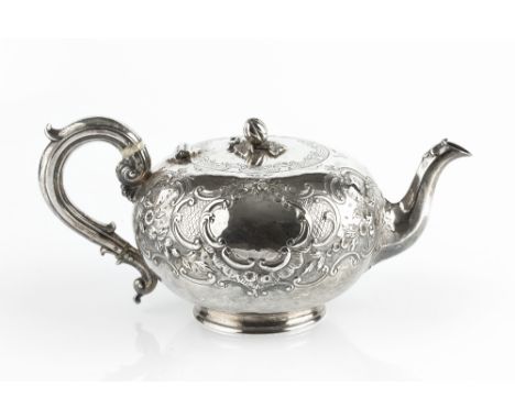 A MID VICTORIAN SILVER TEAPOT, repoussé decorated and chased with flowering foliage and 'C' scrolls, having melon finial, the