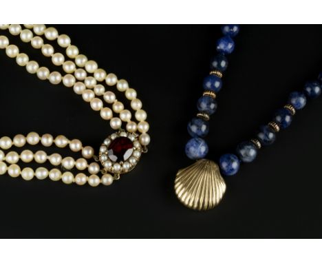 A CULTURED PEARL TRIPLE STRAND NECKLACE, the graduated cultured pearls with an oval mixed-cut garnet and cultured pearl clust