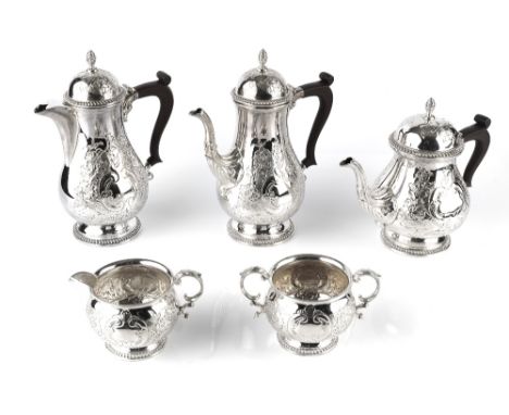 A SILVER FIVE PIECE TEA AND COFFEE SERVICE, of baluster form, engraved and embossed with flowering foliage, and having compos