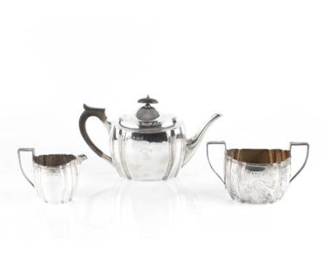 AN EDWARDIAN SILVER THREE PIECE TEA SET, of shaped oval form, with reeded borders, the teapot with ebonised handle and knop, 