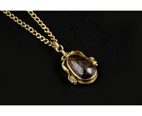 A BOULDER OPAL PENDANT ON CHAIN, the pear-shaped cabochon boulder opal collet set to an Arts and Crafts style mount, decorate