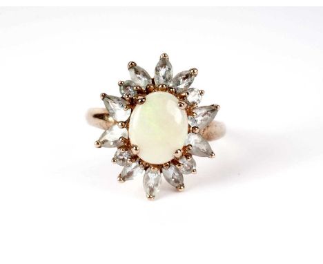 An opal and blue stone cluster dress ring, the central four claw mounted opal within a border of round, marquise and pear sha