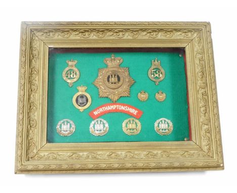 A Northamptonshire Regiment helmet and cap badges, a collection of ten badges and a shoulder badge, framed case.