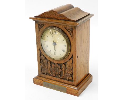 An Edwardian oak cased mantel clock, with scroll leaf and flower design with brass plaque to Harold Wilford, a wedding presen