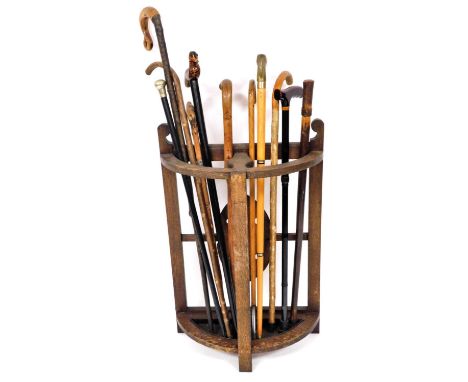 An early 20thC demi lune stick stand, with lead liner and a quantity of walking sticks, to include Shepherd's crook, later wa