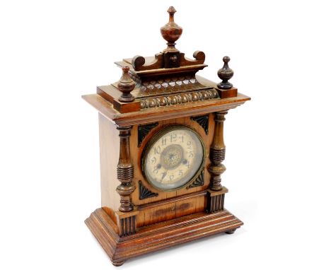 A late 19thC walnut cased mantel clock, the 11cm diameter Arabic dial in a shaped case, surmounted by three urn finials and f