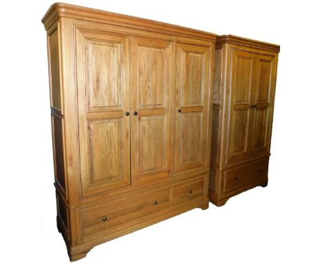 An American light oak two piece bedroom suite, comprising three door and two door wardrobes, each with a moulded cornice, pan