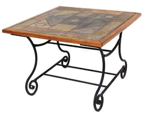 A 20thC tile topped coffee table, on a wrought iron scroll stand, with newspaper rack beneath, with a geometric top and oak f