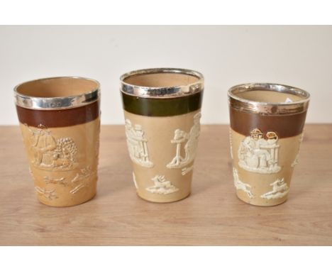 A set of 3 Victorian Royal Doulton Lambeth stoneware beakers, mounted with silver rim dated for Sheffield c1898, decorated wi