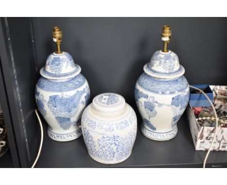 A pair of blue and white ceramic table lamps, decorated with fruit and foliage, h34cm, sold together with a ginger jar, (3)