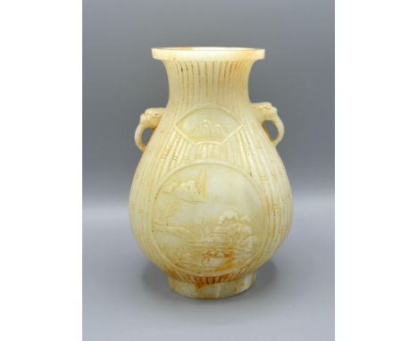 A Chinese Jade Vase carved with two reserves amongst bamboo and with foe head side handles, 19 cms tall 