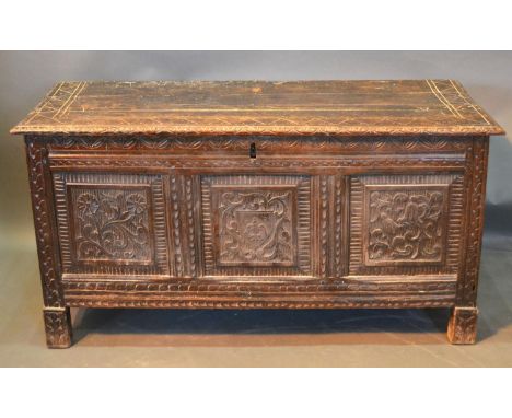 An 18th Century Oak Coffer, the hinged top above a three carved panel front flanked by stiles, 119 cms wide, 48 cms deep, 59 