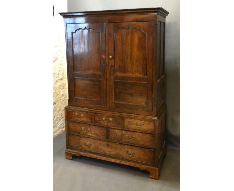 A George III Oak Bacon Cupboard, the moulded cornice above two panelled doors enclosing a hanging space above three simulated