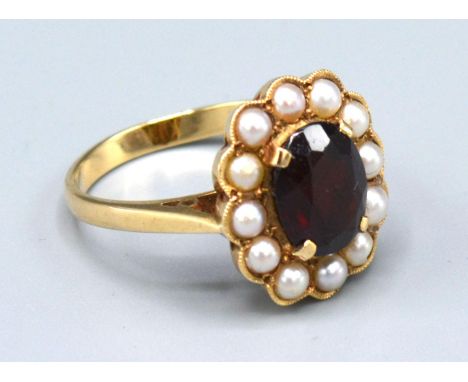 A 9ct. Gold Garnet and Pearl Cluster Ring with a central oval garnet surrounded by pearls within a pierced setting 