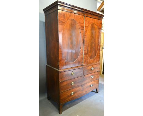A Regency Mahogany Linen Press, the moulded cornice above two oval panel doors enclosing sliding trays, the lower section wit