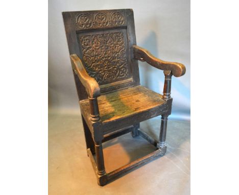 A George III Oak Wainscot Chair, the carved back above a panel seat with scroll arms raised upon turned legs with stretchers 