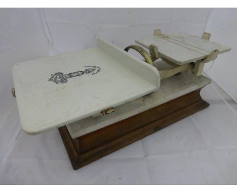 A set of early 20th Century cheese scales complete with marble trays, raised on an oak plinth. 