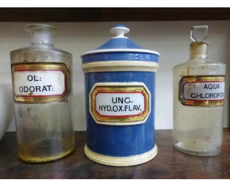 A blue lidded ceramic chemist canister with glass label and two glass bottles with similar labels. 