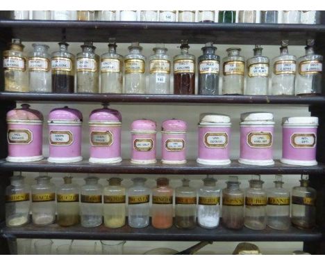 Eight pink ceramic lidded medicine canisters, all with glass medicine labels.