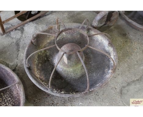 A circular cast iron pig trough with dividers