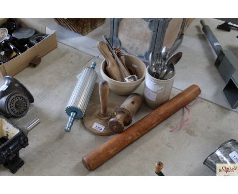 A collection of various kitchenalia including butter pats, potato masher, rolling pin, and cutlery