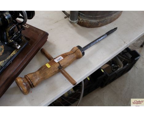 An antique iron boring tool with wooden rustic handle
