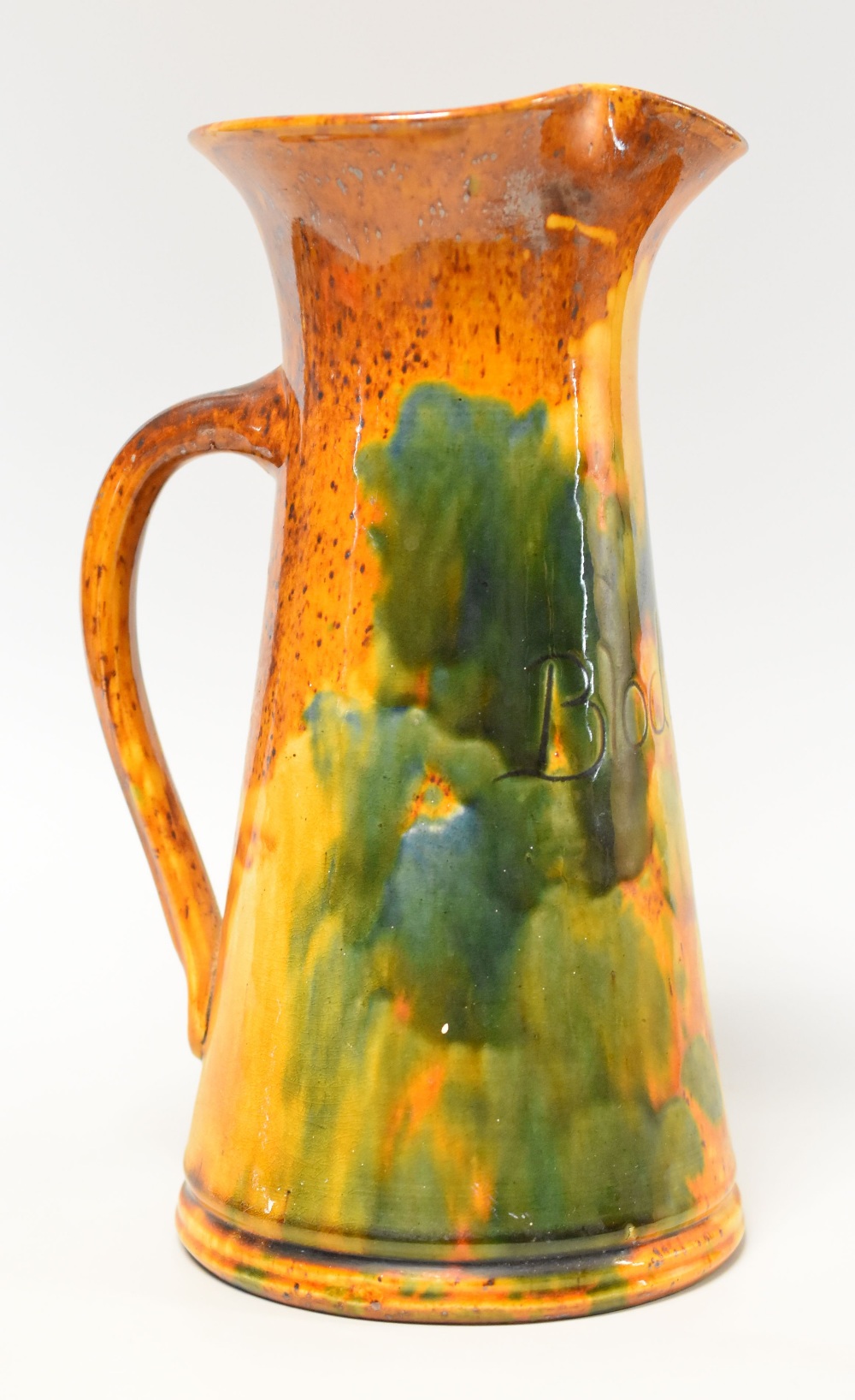 AN EWENNY POTTERY FLOWER JUG in a mottled orange and green glaze and