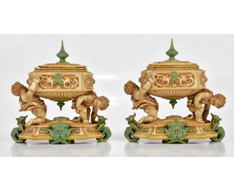 ROYAL WORCESTER; a pair of unusual lidded urn vases of oval form, the urns supported by cherubs on a shaped oval plinth base 