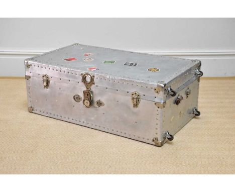 A silvered metal trunk with studded detail and applied vintage labels including 'Munson Steamship Lines Buenos Aires', 'Hotel