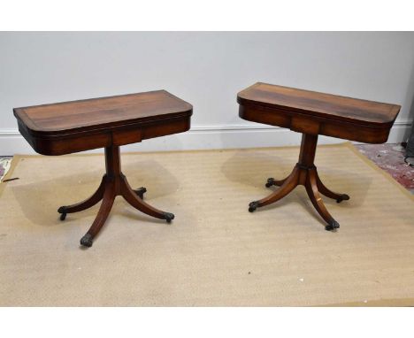 A near pair of Regency rosewood card tables, each with a swivel top on an octagonal column and four swept legs with brass lio