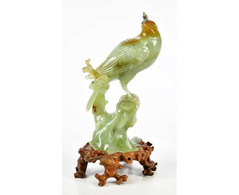 A Chinese carved jade figure of a bird perched upon a rock, sold with shaped wooden base, height including base 21cm.