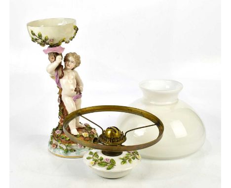 An early 20th century Continental porcelain oil lamp with milk glass dome shade and detachable reservoir, supported by a cher