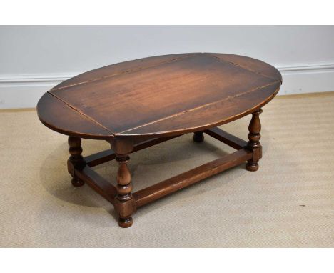 A reproduction oak drop-leaf coffee table of rectangular form, on bun feet, width 95cm, height 50cm.