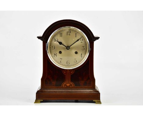 An Edwardian inlaid mahogany arch topped mantel clock, the circular dial set with Arabic numerals, the movement stamped Briti