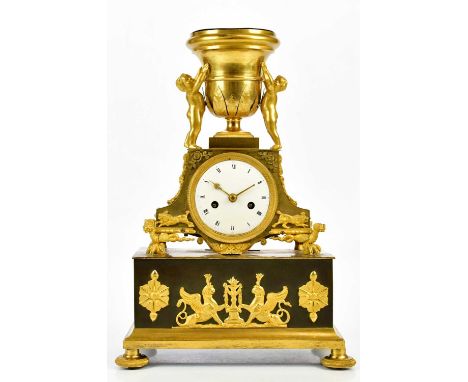 A late 19th century French ormolu mantel clock with cherubs supporting an urn finial above the enamel dial set with Roman num