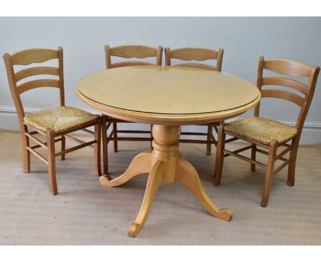 A modern kitchen table with four rush seated chairs.