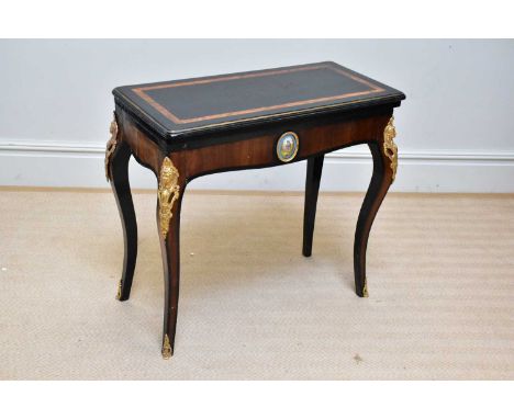 A 19th century ebonised and rosewood gilt metal mounted fold-over games table, with porcelain oval mount of a figure in lands