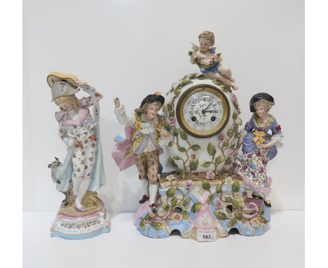 A continental ceramic clock with figures and a cherub, together with another figure of a man with a dog biting his coat Condi