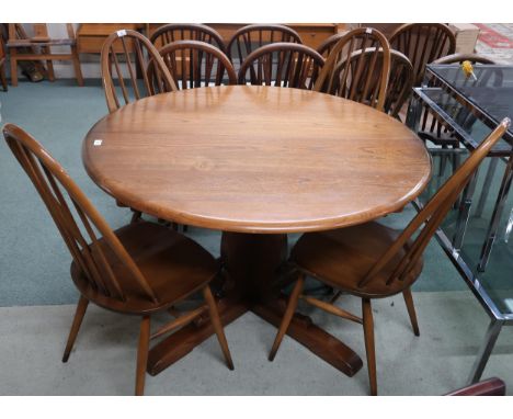 A 20th century Ercol elm circular topped extending dining table and four mid 20th century Ercol elm and beech rail back dinin