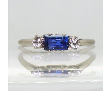 A white metal diamond and sapphire three stone ring, set with estimated approx 0.10cts of old cut diamonds and an step cut sa