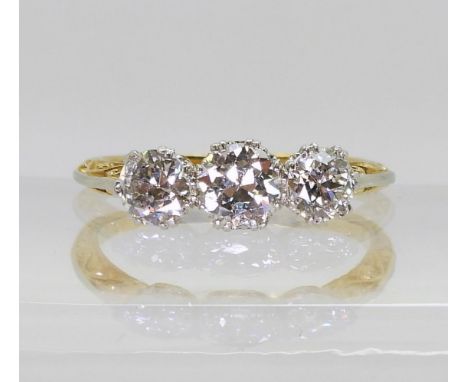 A 1930s vintage three stone diamond ring, with a pretty platinum and 18ct yellow gold scroll mount, set with three old cut di