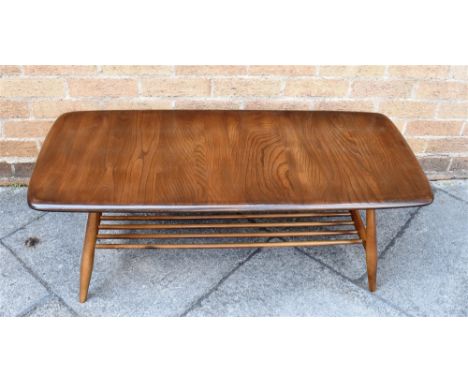 AN ERCOL COFFEE TABLE  the oblong top 44cm x 105cm, with magazine shelf rack undertier, 36cm high